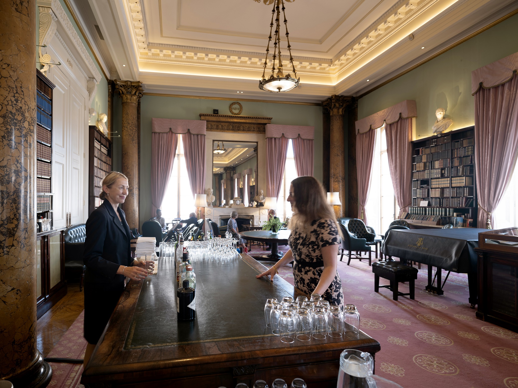 Member of staff serving a drink to a member at the Drawing Room bar